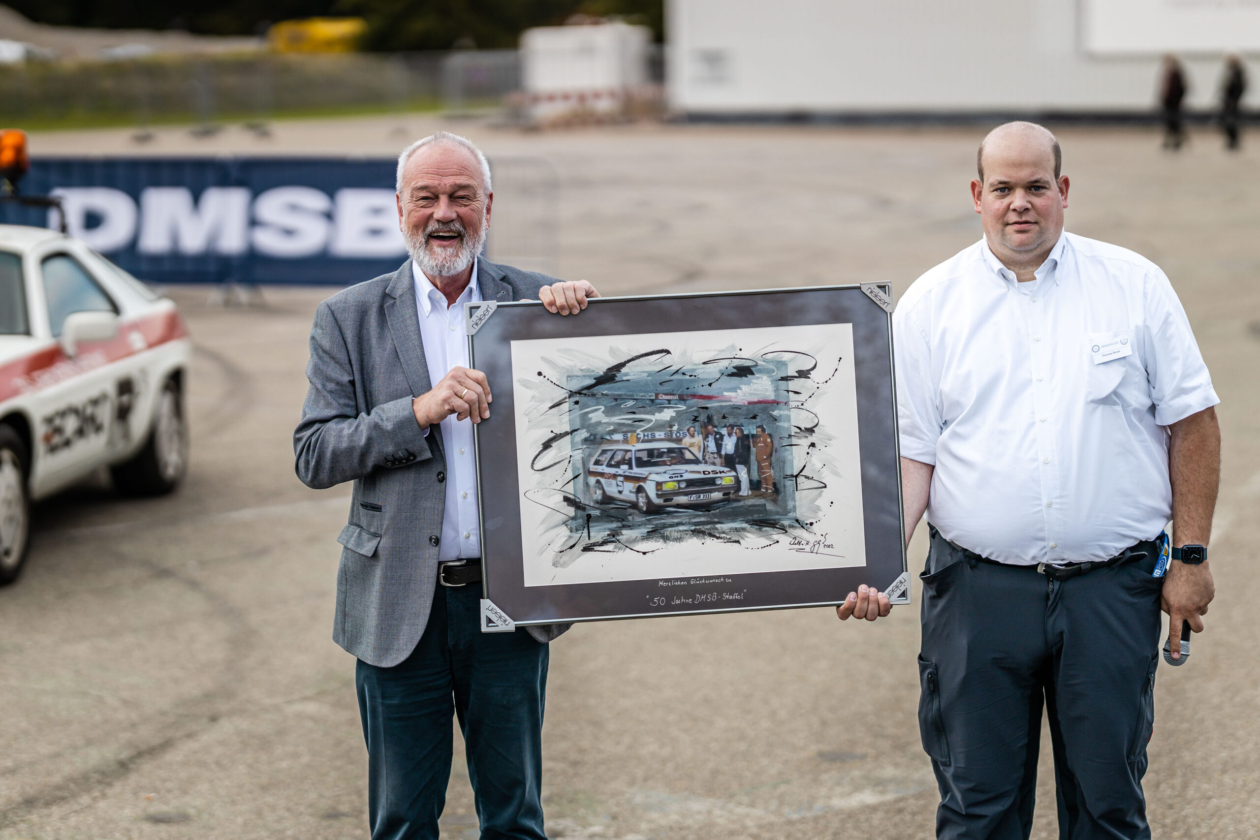 50 Jahre DMSB-Staffel: Im Rahmen des Verbandstages überreicht DSK-Präsident Dr. Karl-Friedrich Ziegahn ein Bild an Staffel-Koordinator Thomas Brost. Das Werk von Kunstmaler Walter-Heinz Glaß zeigt ein Einsatzfahrzeug der damaligen ONS-Staffel.
